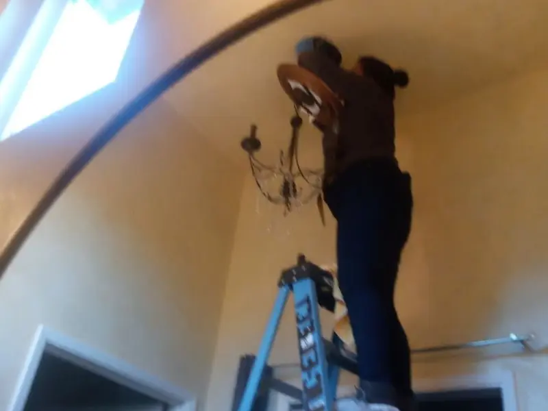 Electrician installing a chandelier in a Schuyler residence